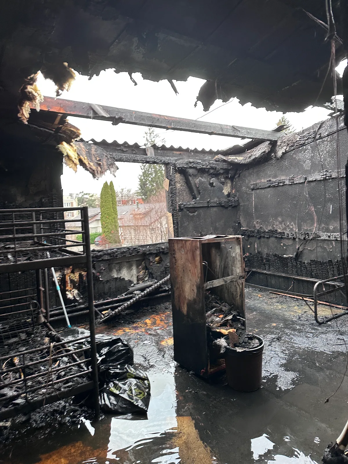 Ein komplett ausgebranntes Zimmer mit schwarzen  Wänden und zerstörtem Dach. 